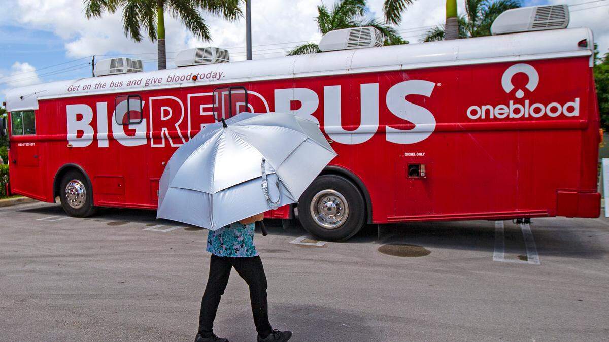 A healthcare worker walks by the Big Red Bus from OneBlood outside Cano Health, 3448 NW 79th St. in Hialeah, on Wednesday, July 29, 2020. The City of Hialeah in association with Cano Health launched a blood drive calling for convalescent plasma donations. Regular blood donors also received COVID-19 antibody tests.