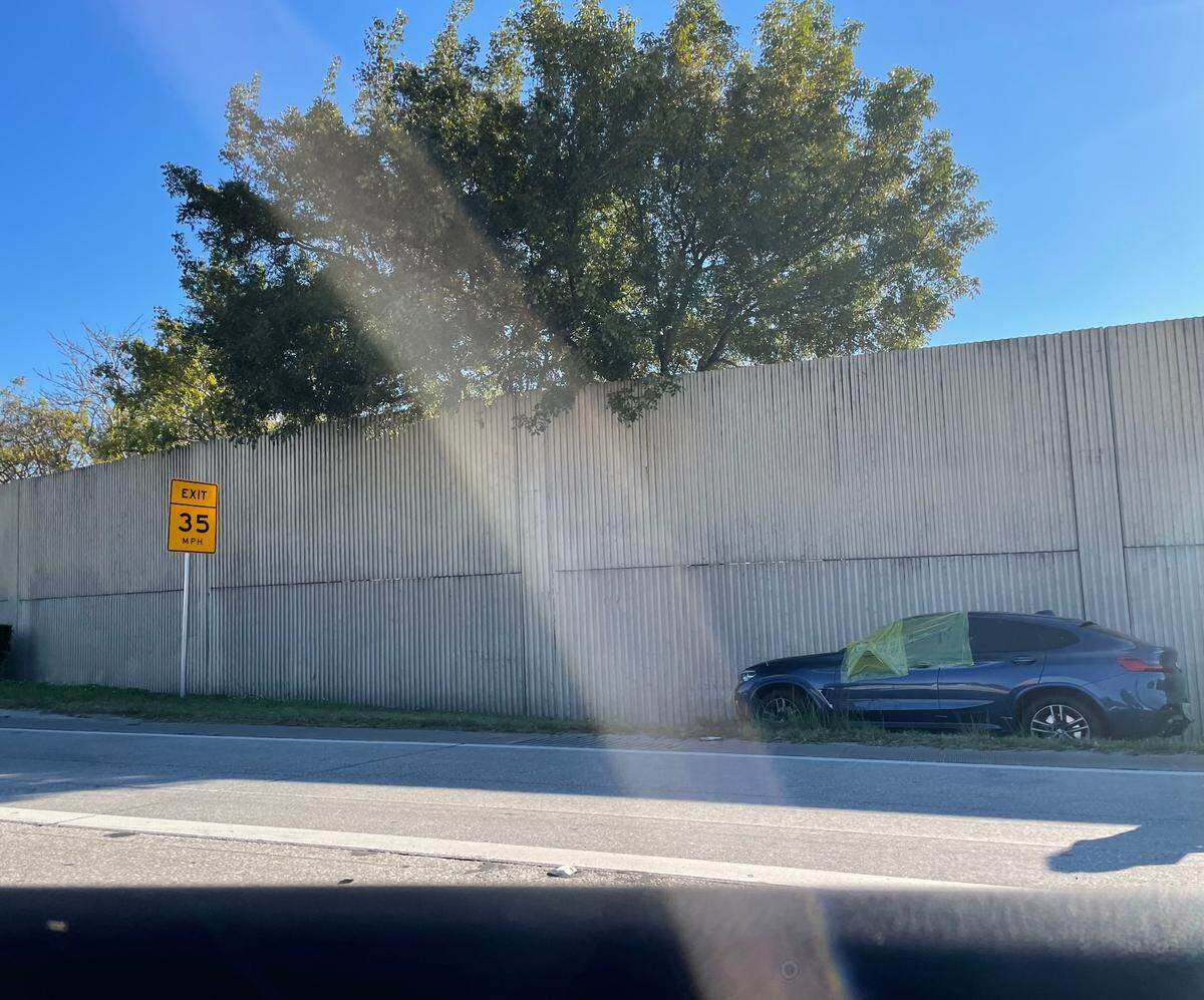 A woman was taken to the hospital after she was shot at while driving on Interstate 95 early Monday. Her car is shown on the side of the highway with a yellow tarp covering the driver’s side window near the Northwest 103rd Street exit.
