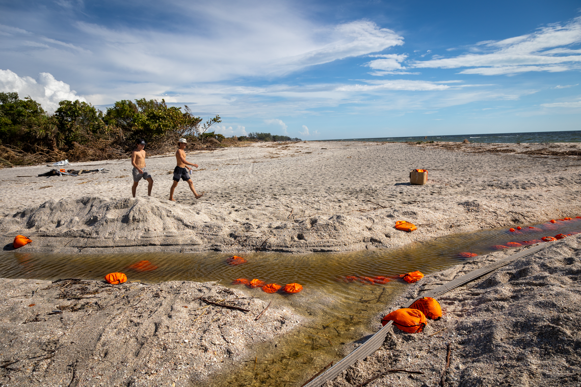 Locals walk past Midnight Pass, a naturally formed waterway that had been filled in with sand but reopened after Hurricane Helene, restoring the flow between the Gulf and Little Sarasota Bay.