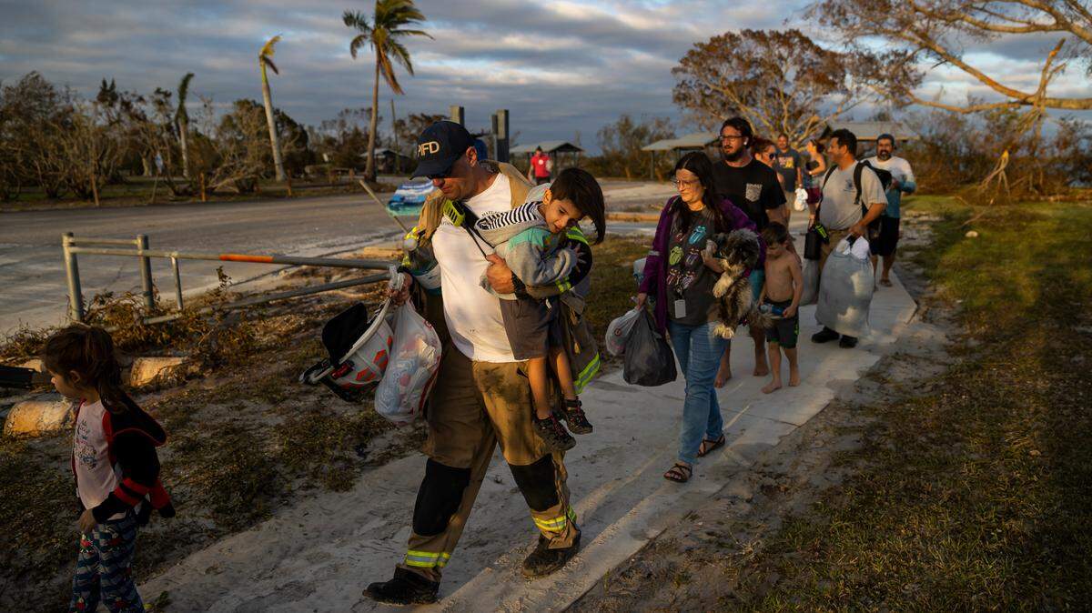 Pine Island Fire Department Captain Bobby Barr holds Greyson Ribas, 3, before ferrying him and residents of Matlacha across water due to broken sections of Pine Island Road on Thursday, Sept. 29, 2022, in Matlacha, Fla.