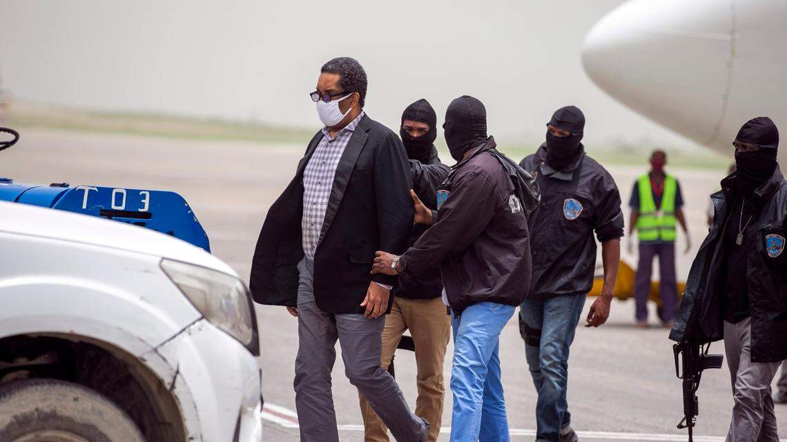 Former paramilitary leader Emmanuel “Toto” Constant, left, is detained by Haitian police after his arrival at the Toussaint Louverture International Airport in Port-au-Prince, Haiti, Tuesday, June 23, 2020.