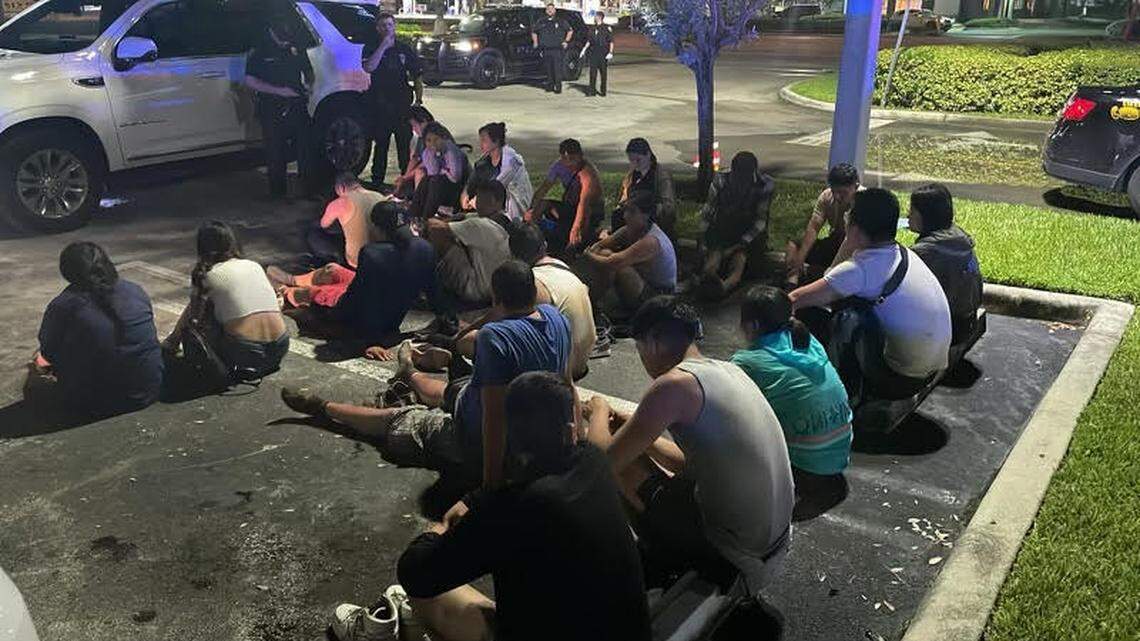 A group of migrants from China and Ecuador sit in a parking lot in Florida City Sunday night, Aug. 19, 2024. The Monroe County Sheriff’s Office said they were smuggled in to Key Largo earlier that night.