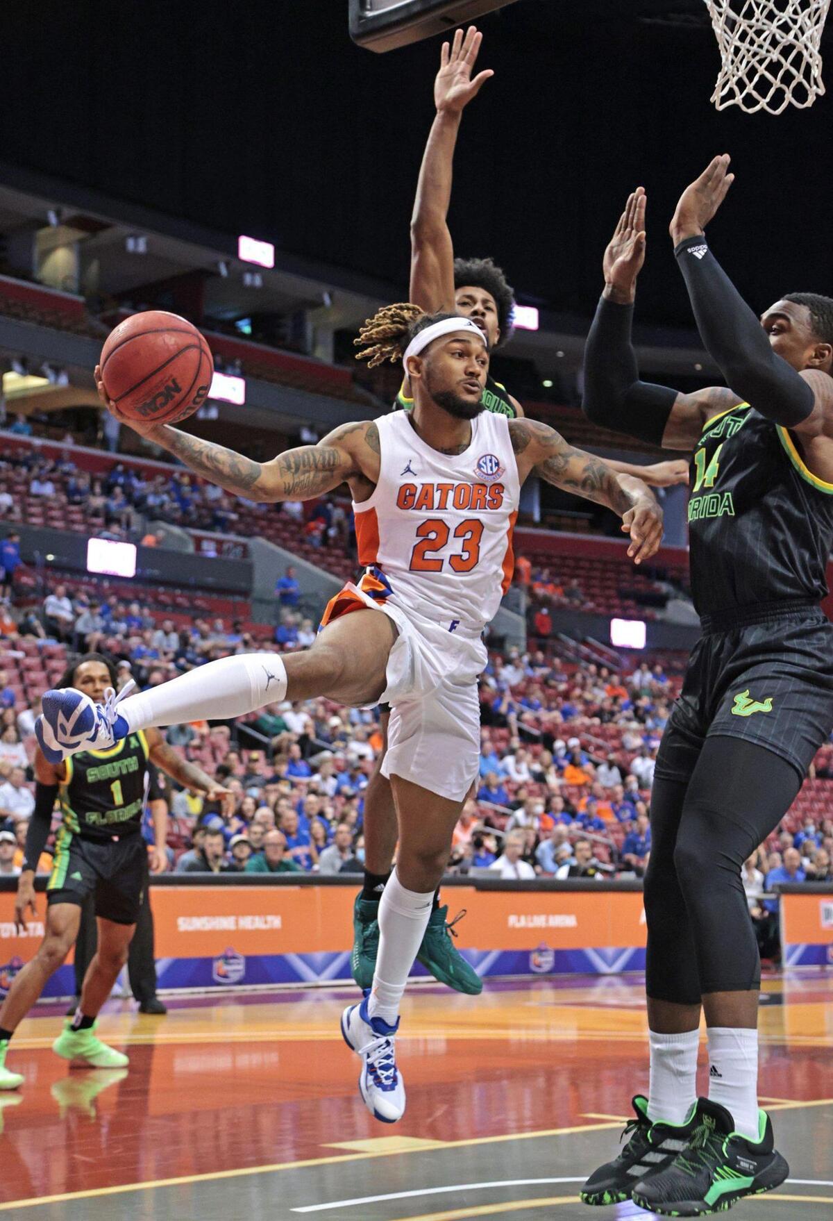 Florida Gators guard Brandon McKissic (23) passes under the basket as South Florida Bulls forward Bayron Matos (14) defends in the Orange Bowl Basketball Classic at the FLA Live Arena in Sunrise on Saturday, December 18, 2021.
