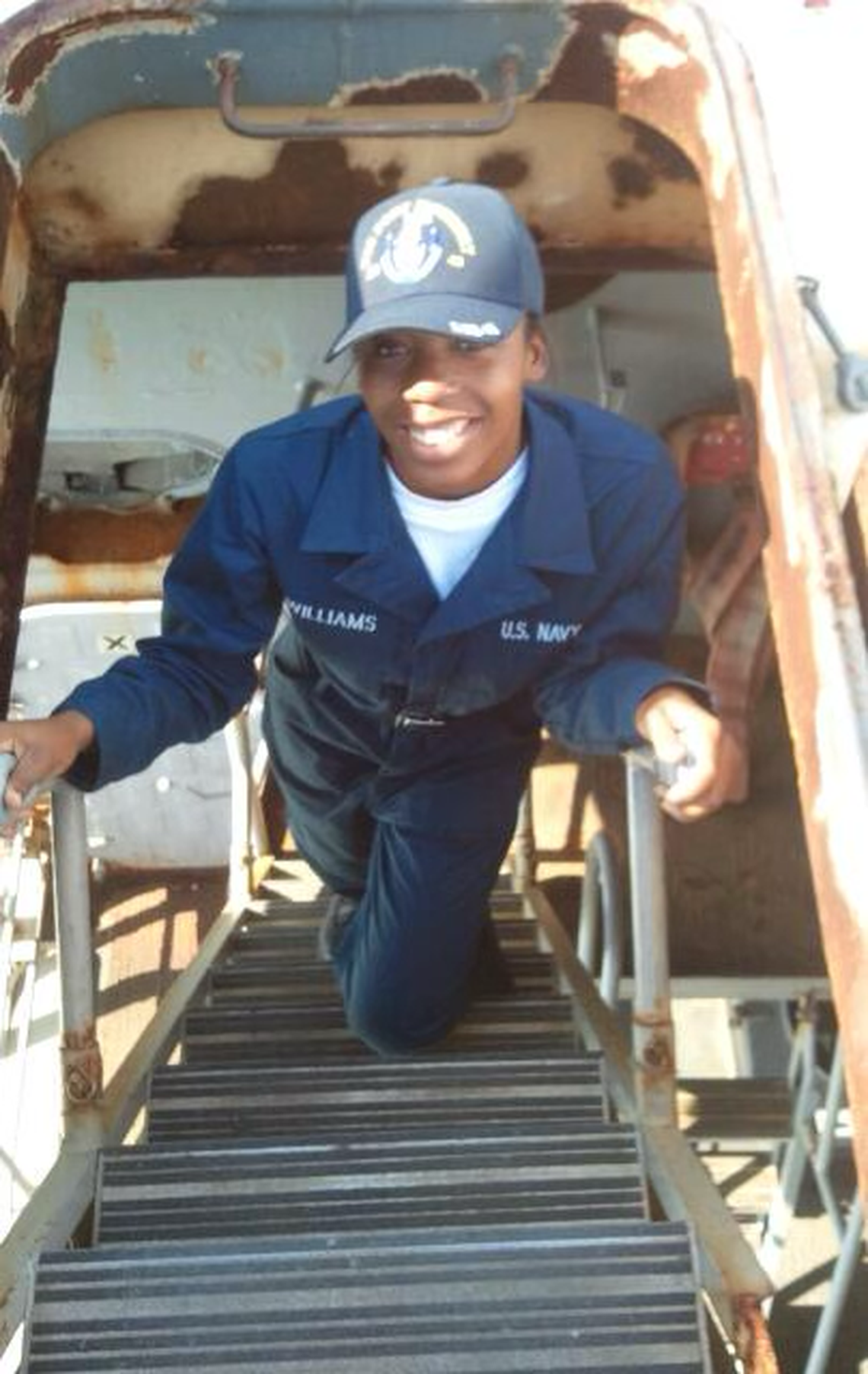 Navy veteran Shay Williams climbs up a ladder on a ship.
