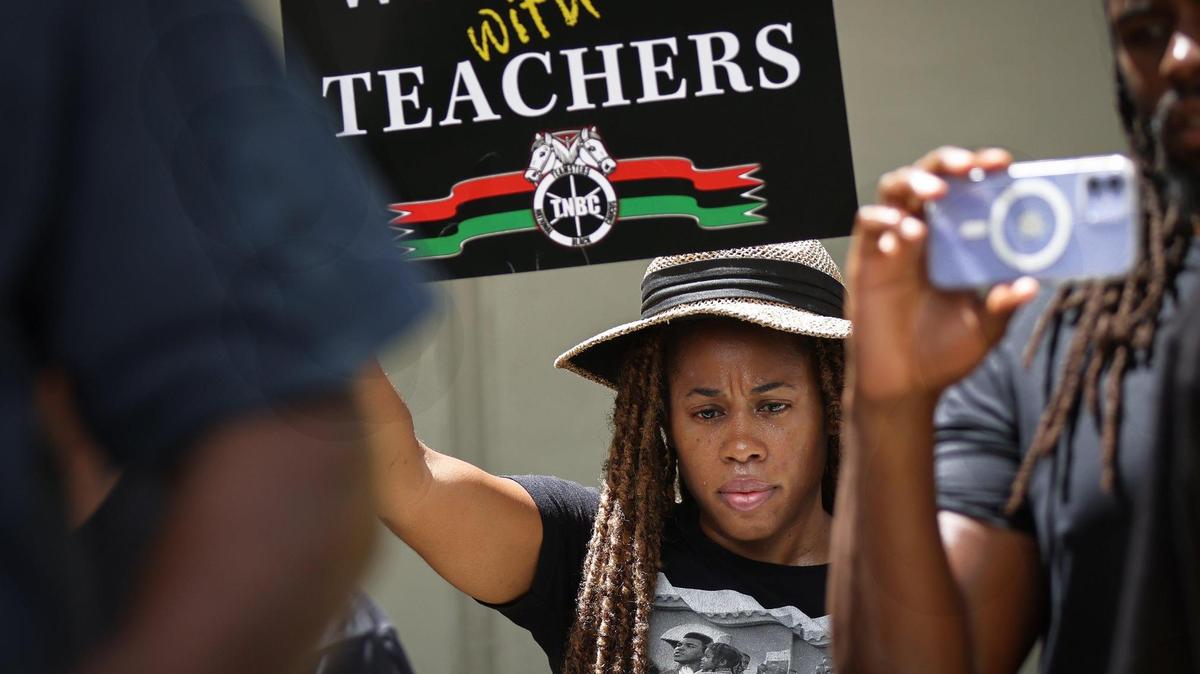 La emprendedora de Miami Noelle Barnes, de 40 años, en el centro, escucha las declaraciones de Marvin Dunn durante una manifestación frente al edificio administrativo de la Junta Escolar de Miami-Dade, el miércoles 16 de agosto de 2023. El grupo de unas 350 personas protestaba contra los nuevos estándares de la historia afroamericana aprobados por el estado en julio, que dicen que algunos esclavos pudieron haberse beneficiado de su esclavitud.