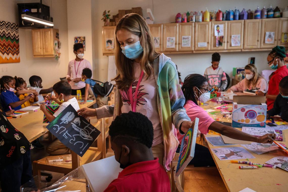 Isabella Dell’Oca, center, the director of Lotus Village, looks at the work of a young artist during a class inside the art and activities lab.