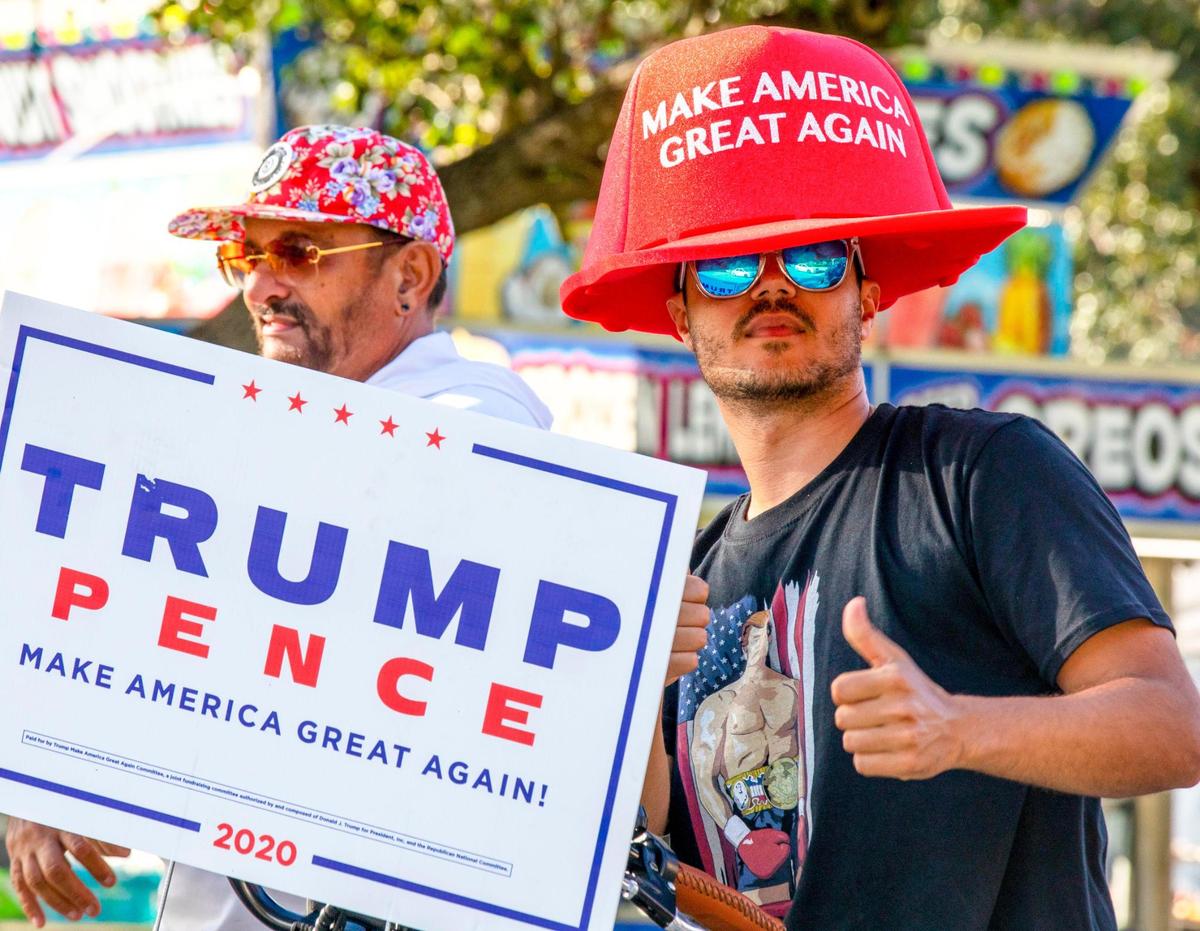 A Trump supporter shows a thumbs-up while holding a ‘TRUMP/PENCE’ sign after a anti-socialism car caravan at Tamiami Park near Miami-Dade County Fair grounds in Sweetwater, Florida, on Sunday, October 18, 2020.