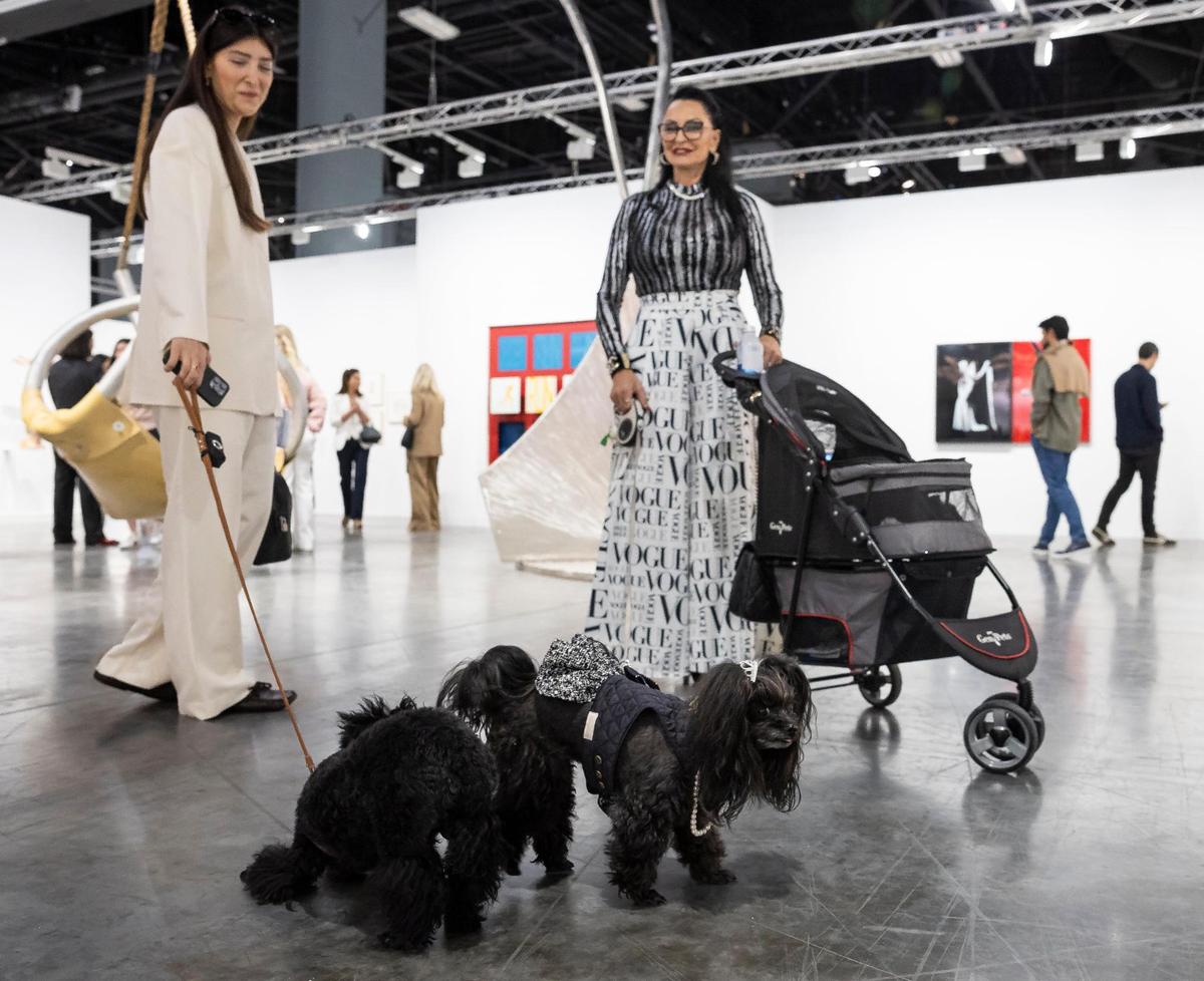 Begum Yasar, left, and her mini-poodle, Philos, meet Rozann Arena and her shih tzu-poodle, Lola Diamond, as they attend Art Basel at the Miami Beach Convention Center on Wednesday, Dec. 4, 2024, in Miami Beach, Fla.