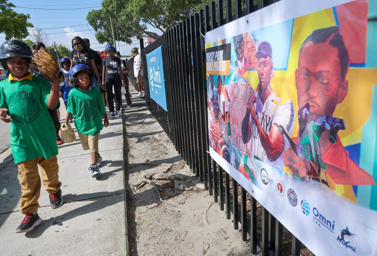 Young baseball enthusiasts and press conference attendees walk toward the restored murals at Historic Dorsey Park on Wednesday, August 20, 2025, in Miami, Florida.