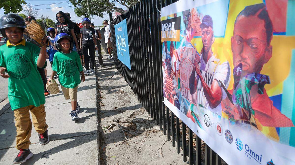 Young baseball enthusiasts and press conference attendees walk toward the restored murals at Historic Dorsey Park on Wednesday, August 20, 2025, in Miami, Florida.
