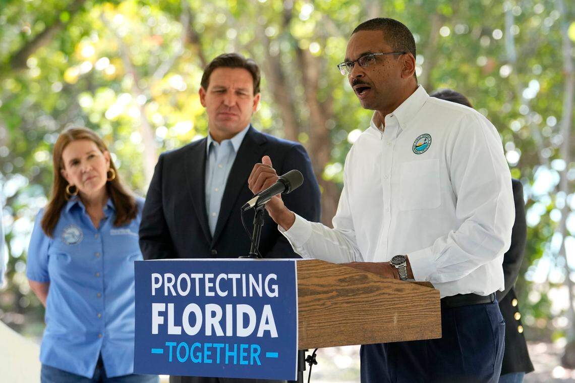 Shawn Hamilton, secretary of the Florida Department of Environmental Protection, right, speaks during a news conference at Bill Baggs Cape Florida State Park, Thursday, Dec. 1, 2022, on Key Biscayne, Fla. Florida Gov. Ron DeSantis, center, announced increased funding for the environmental protection of Biscayne Bay.