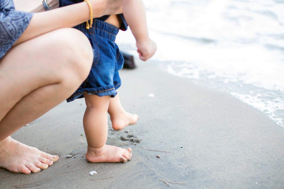 parent and child with feet by water