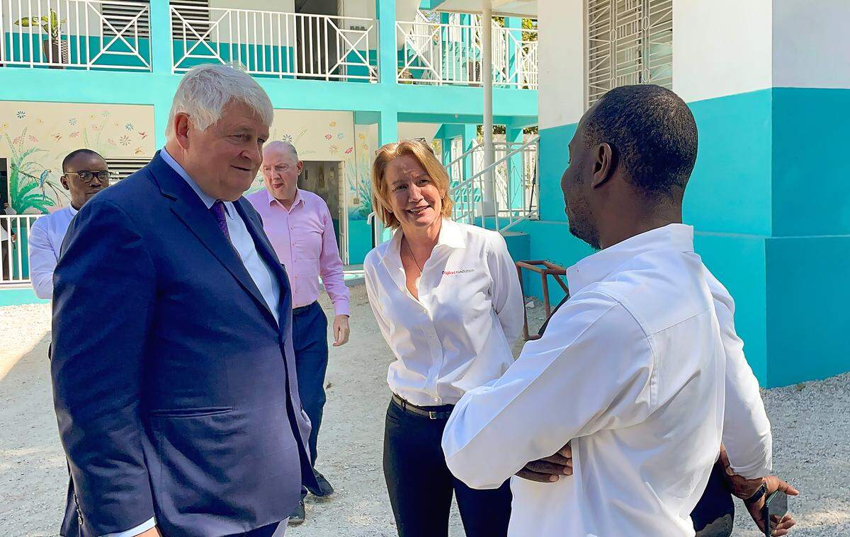 Digicel Group Chairman Denis O’Brien tells a group of priests at Institution Mixte Notre Dame de l’Assomption in Port-au-Prince that his Digicel Foundation will provide them with a new building. Joined by foundation chief executive officer, Sophia Stransky, left, O’Brien toured the premises on Feb. 16, 2023.