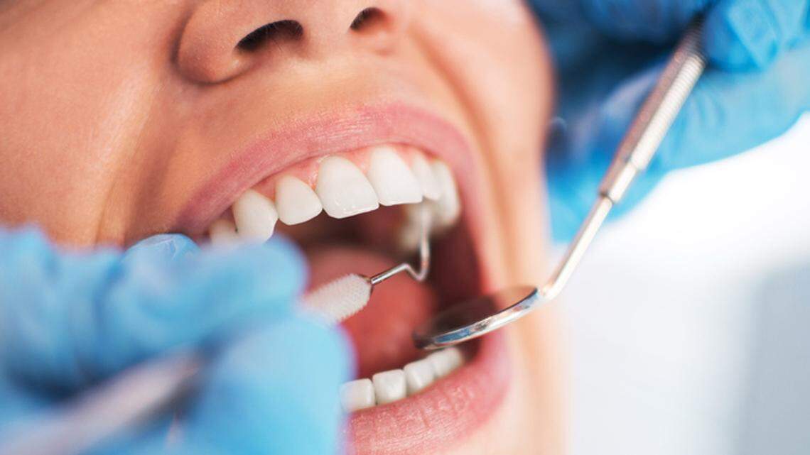 A dentist examines a person’s mouth.