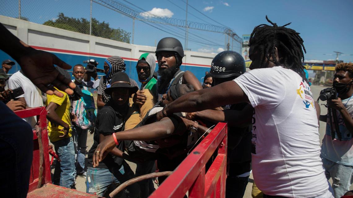 Journalists carry photojournalist Maxiben Lazarre onto a truck after he was shot dead while covering a protest by factory workers demanding higher salaries in Port-au-Prince, Haiti, Wednesday, Feb. 23, 2022. Men wearing police uniforms drove by the protest and fired into the crowd where Lazarre was covering the demonstration.