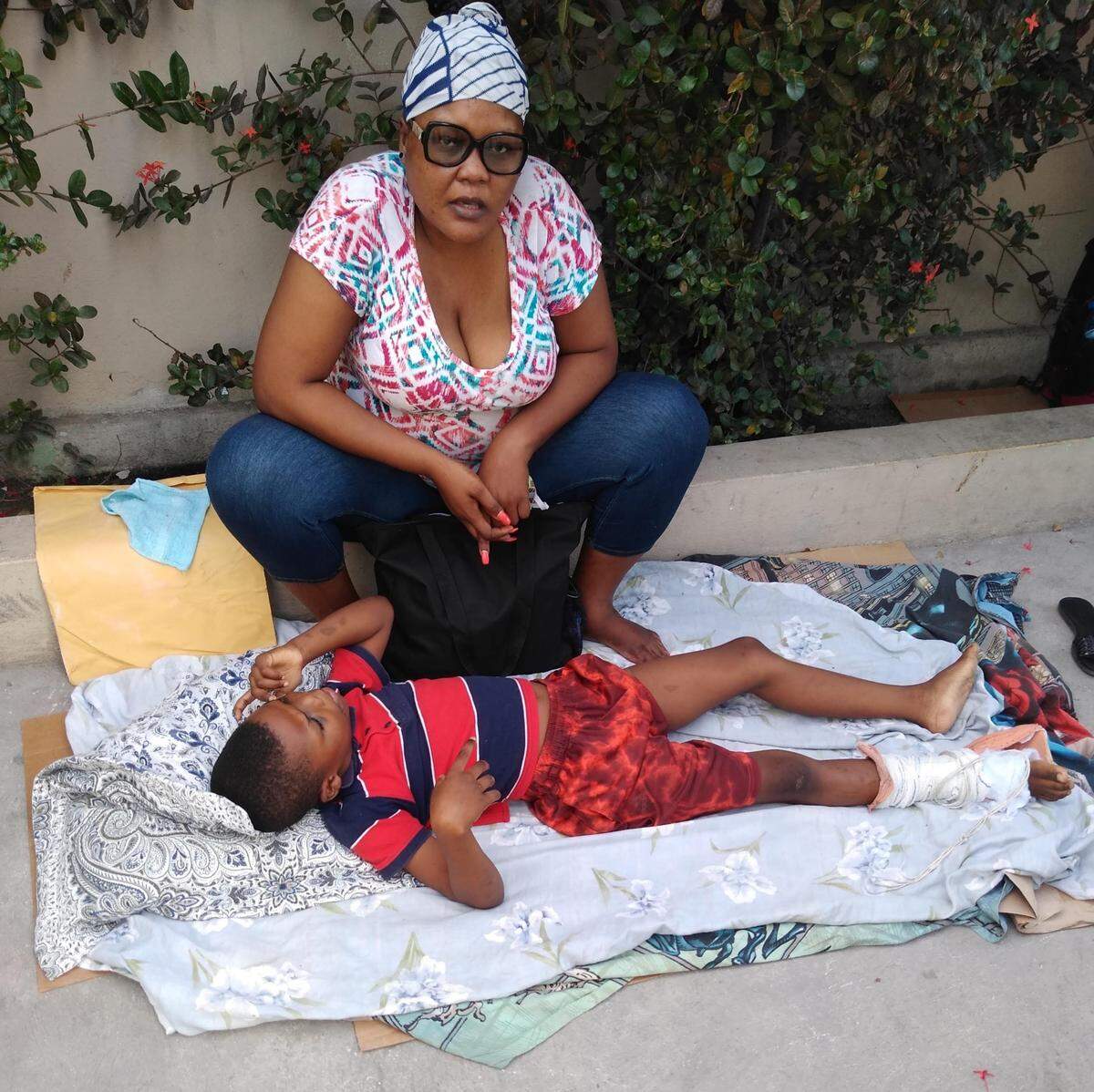 Deandre Samedi, 12, and his mother in a Port-au-Prince hospital parking lot. Sometimes that was the only way he received medical care.