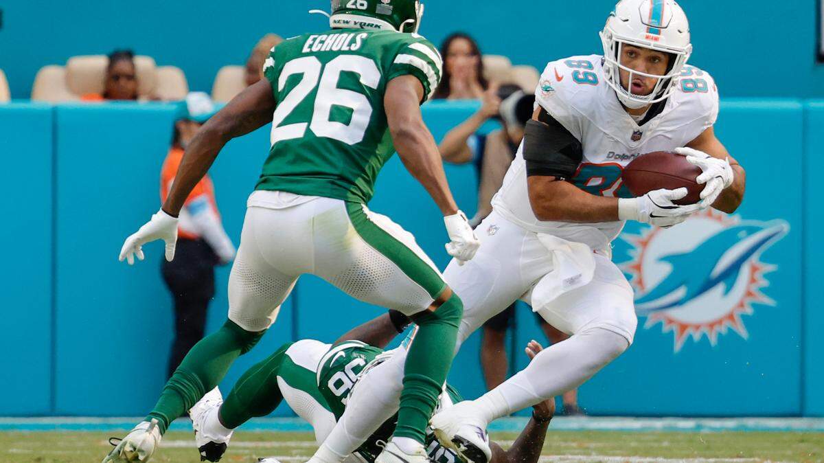 Miami Dolphins tight end Julian Hill (89) runs for yardage as New York Jets cornerback Brandin Echols (26) defends in the first half of their NFL football game at the Hard Rock Stadium in Miami Gardens, Florida on Sunday, December 8, 2024.