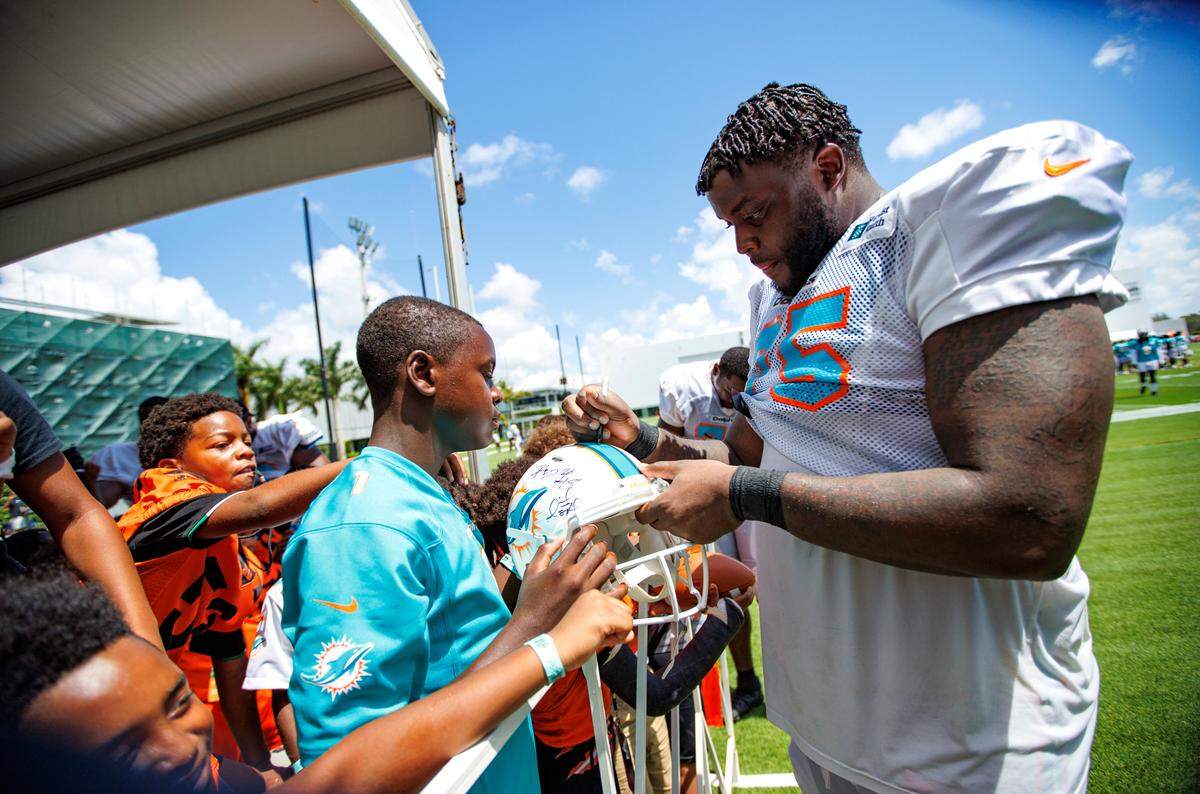 Miami Dolphins offensive tackle Greg Little (75) signing autographs to fans after NFL football training camp at Baptist Health Training Complex in Hard Rock Stadium on Friday, August 5, 2022 in Miami Gardens, Florida.