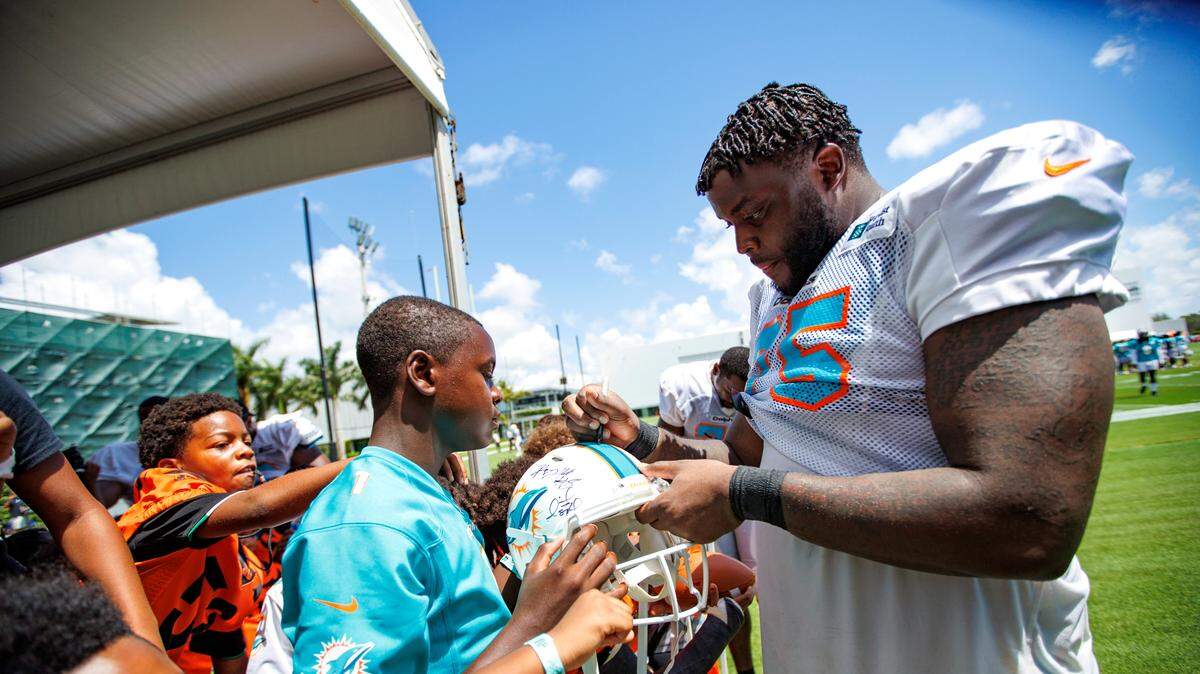 Miami Dolphins offensive tackle Greg Little (75) signing autographs to fans after NFL football training camp at Baptist Health Training Complex in Hard Rock Stadium on Friday, August 5, 2022 in Miami Gardens, Florida.