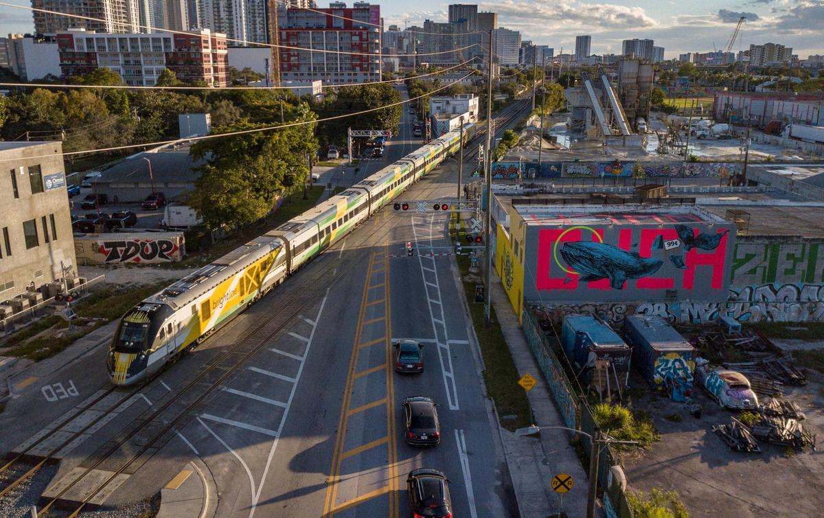 The Brightline train travels through the intersection of North Miami Avenue and 19th Street on the southeast edge of Miami’s Wynwood area on Thursday, Jan. 13, 2022.
