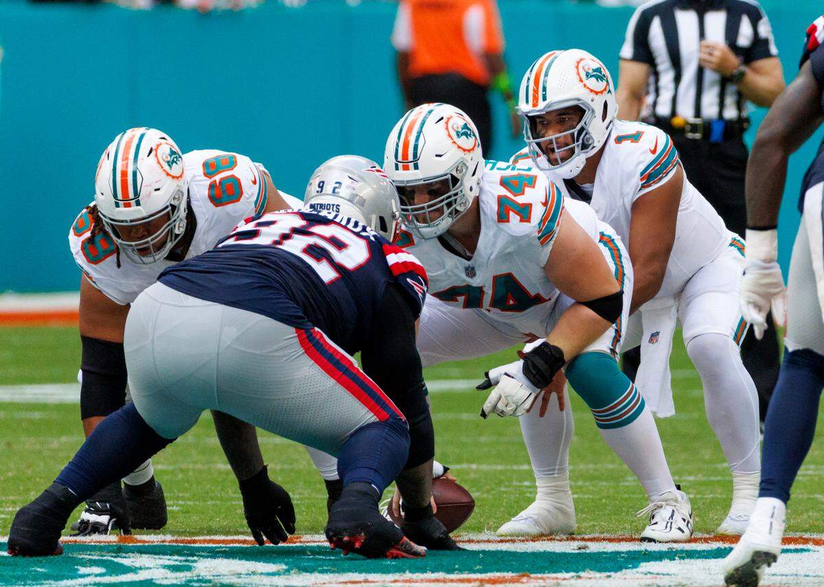 Miami Dolphins offensive tackles Robert Hunt (68) and Liam Eichenberg (74) protect teammate Dolphins quarterback Tua Tagovailoa (1) from New England Patriots defensive tackle Davon Godchaux (92) during second quarter of an NFL football game at Hard Rock Stadium on Sunday, Oct. 29, 2023 in Miami Gardens, Fl.