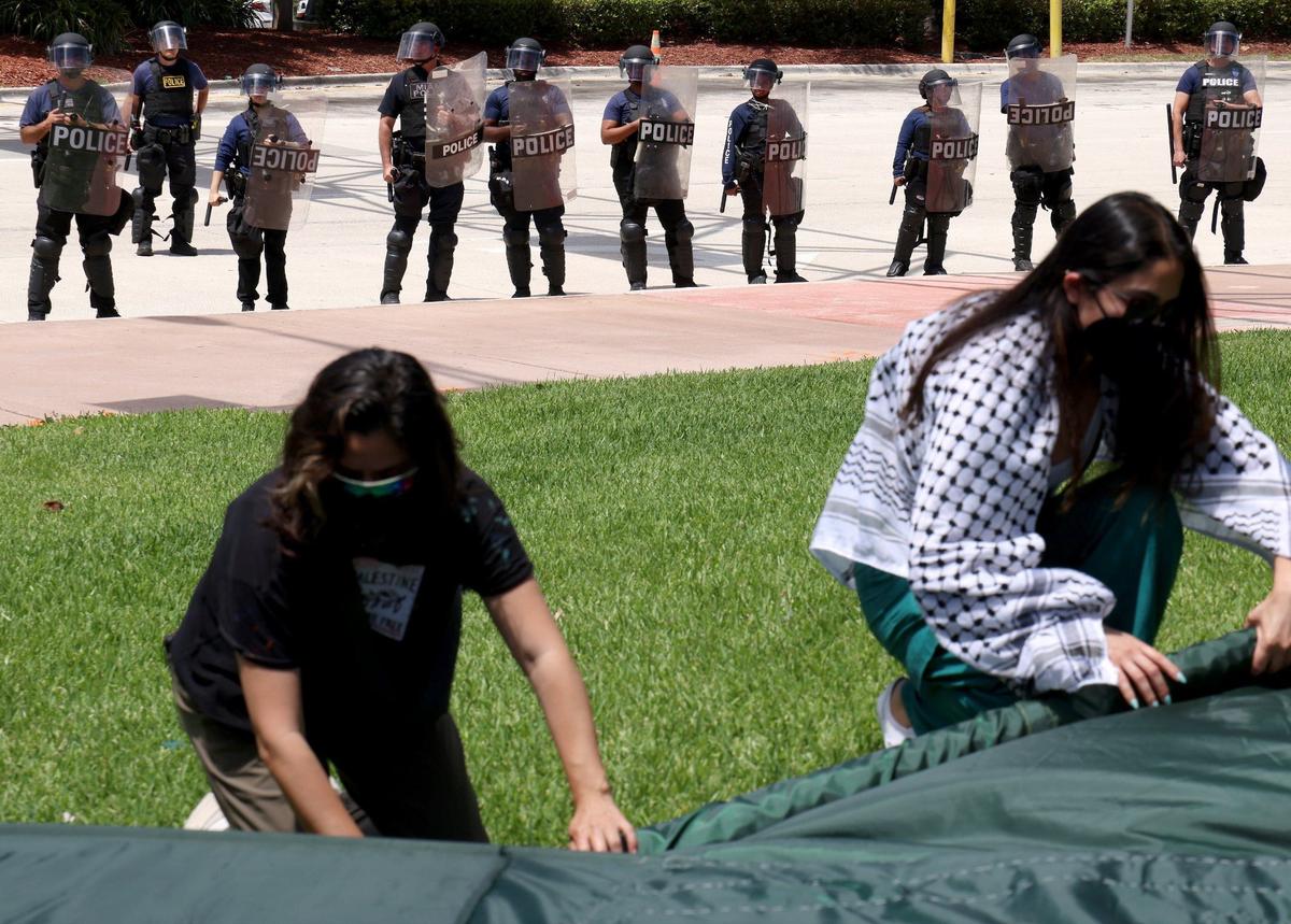 Miami Police officers in riot gear stand near as a group protesting for ceasefire in Gaza in Bayside Monday, April 15, 2024. Police arrested seven protesters accused of blocking the intersection of 3rd Street and northbound Biscayne Boulevard.