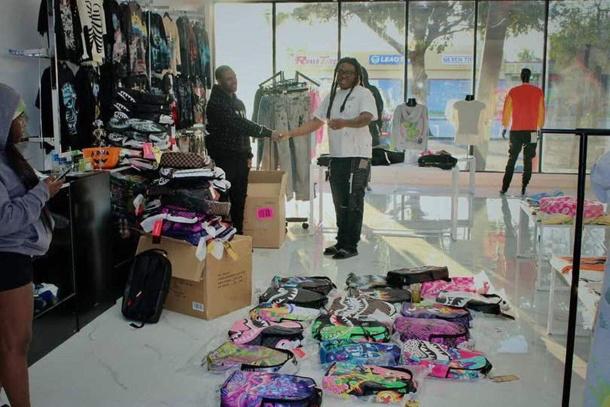 1GR cofounder Jovany Appolon (right) organizes apparel at the North Miami store.