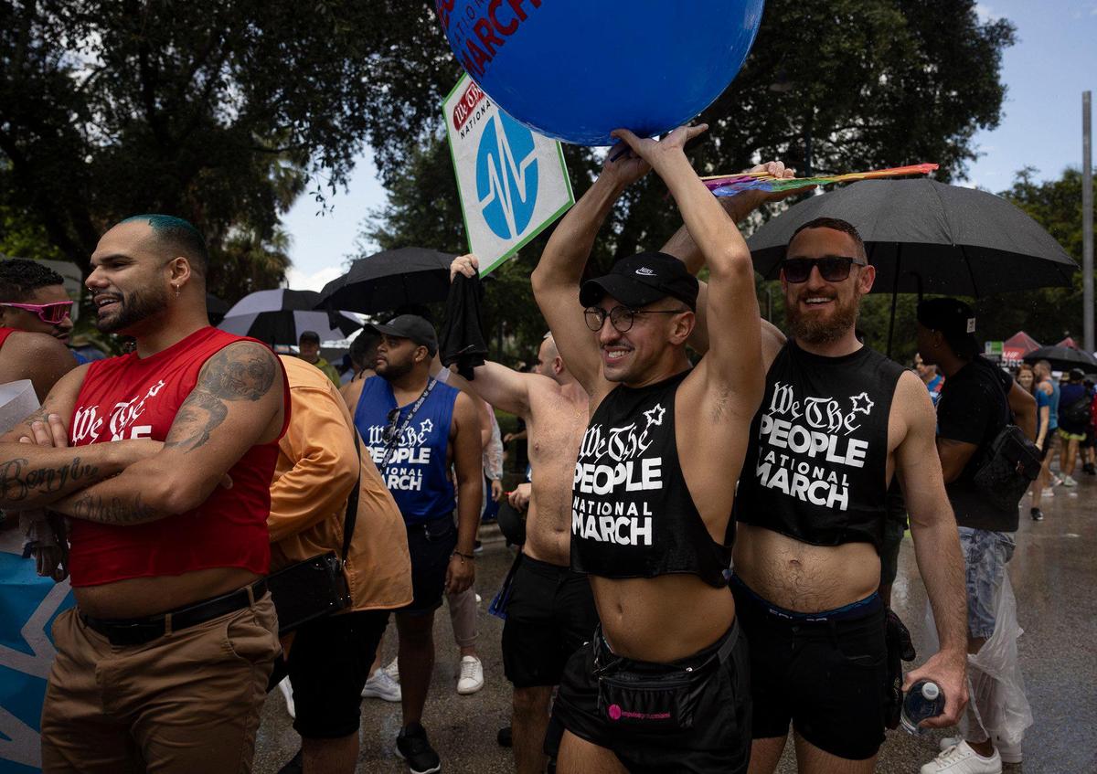Nick Arango, center, from Orlando, dances in the rain during an Anti-Hate March led by We the People on Sunday, July 2, 2023, in downtown Fort Lauderdale.