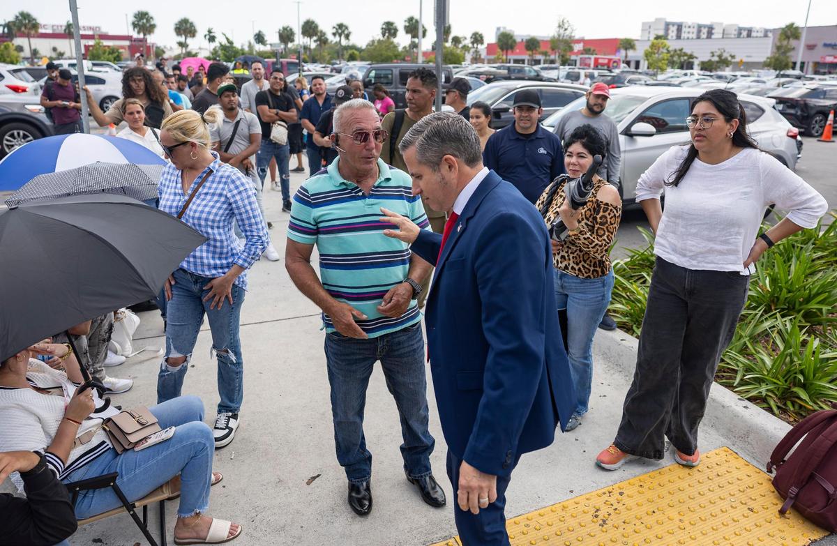 Miami-Dade Tax Collector Dariel Fernandez talks with Gerry Leon, 60, of Miami Gardens, who arrived without an appointment, as he waits outside the Miami Central DMV office on Wednesday, April 16, 2025, in Miami.