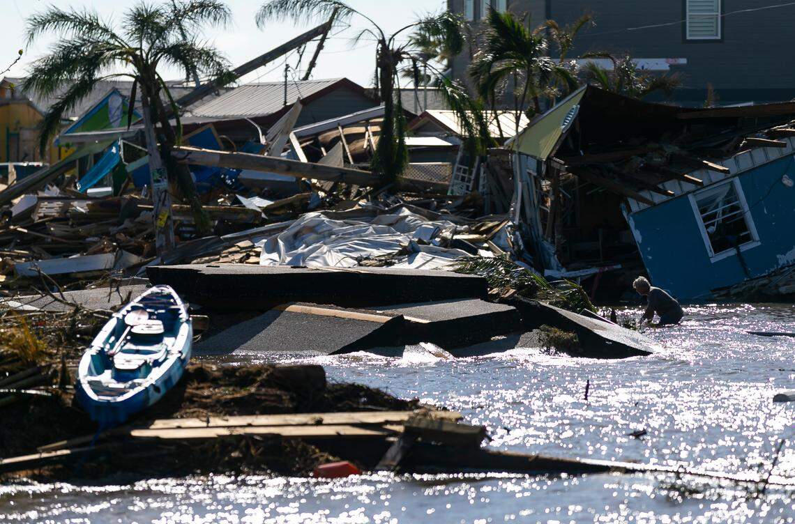 A man moves through gulf water flowing through a broken section of Pine Island Road on Thursday, Sept. 29, 2022, in Matlacha, Florida. Hurricane Ian made landfall on the coast of Southwest Florida as a Category 4 storm on Sept. 28.