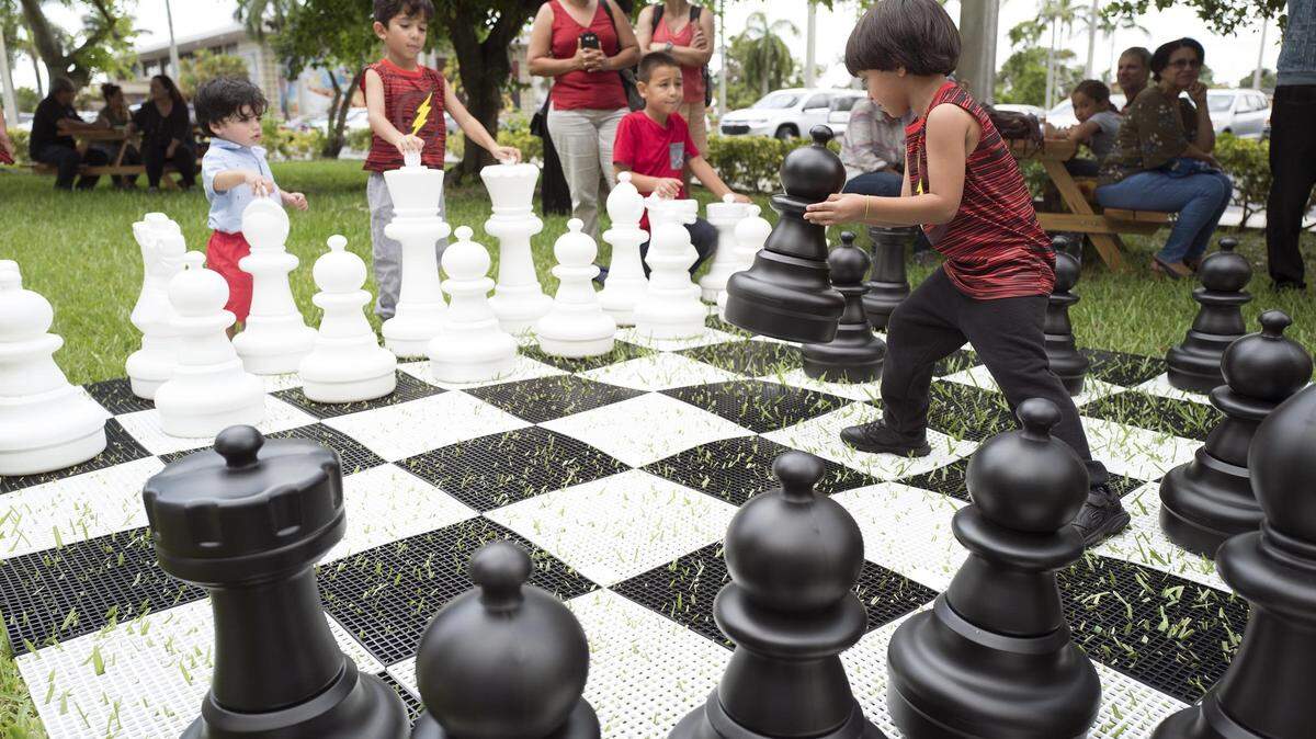 Children play on a giant chess board during the opening of Hialeah’s new Domino Park on Thursday, July 12, 2018.
