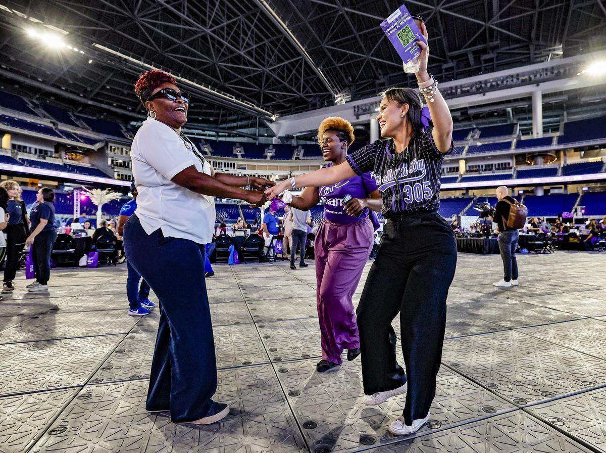 Julie Robison, Mimi King and Julissa Rivera dance as they view the updated fundraising totals displayed during Give Miami Day at loanDepot Park in Miami, Florida, on Thursday, Nov. 20, 2025.  