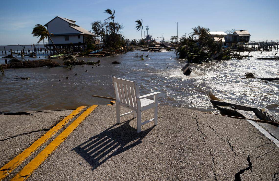 Gulf water flows through a broken section of Pine Island Road on Thursday in Matlacha. The white chair came from the surrounding ruins.