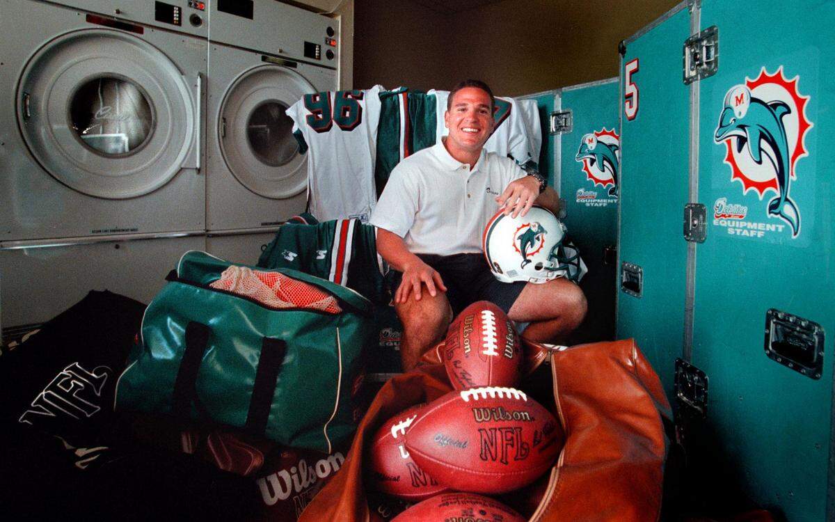 Dolphins equipment manager Tony Egues poses with the huge washing machines that use football-strength laundry chemicals so powerful that we must pray they never fall into enemy hands.