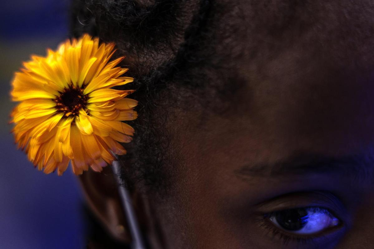 A young girl places an edible flower in her hair during a visit to the hydroponic farm at Lotus Village in Miami’s Overtown neighborhood.