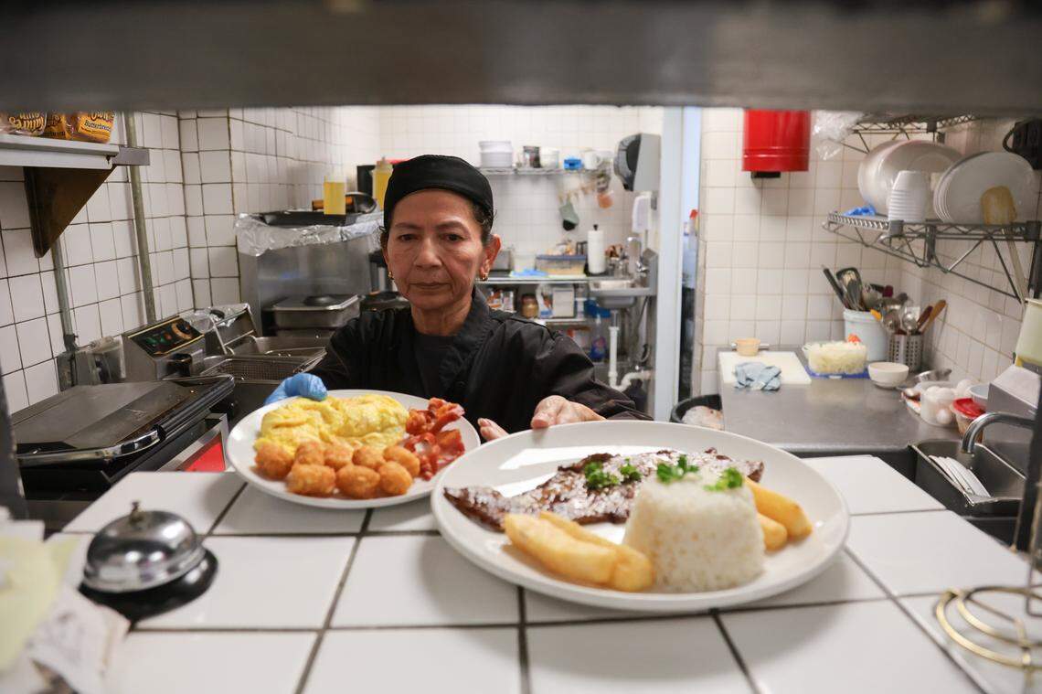 Chef Janet Hernandez places finished dishes by the kitchen pass for restaurant owner Mario Magalhaes to pick up and serve at Las Palmas Restaurant at 209 SE First St., in downtown Miami, Florida, on Thursday, Nov. 6, 2025.