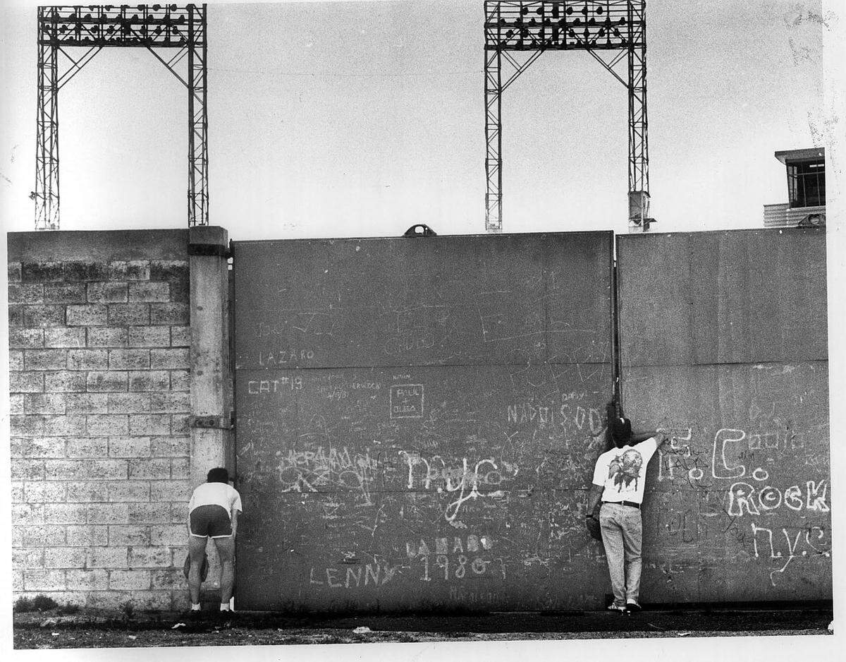 Gary Delgross of Minniapolis, minnisota and Michael Bergin of Miami watch the Orioles practice on the other side of the fence on Friday afternoon outside the Bobby Maduro Miami Stadium.