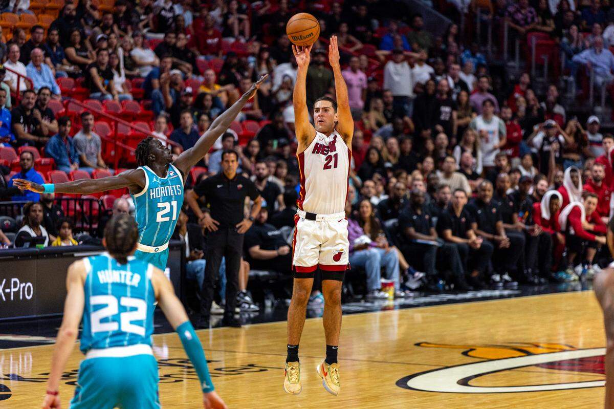 El delantero del Heat Cole Swider dispara un triple ante la defensa de JT Thor (21), de los Hornets de Charlotte, en el partido de pretemporada celebrado el 10 de octubre de 2023 en Miami. 