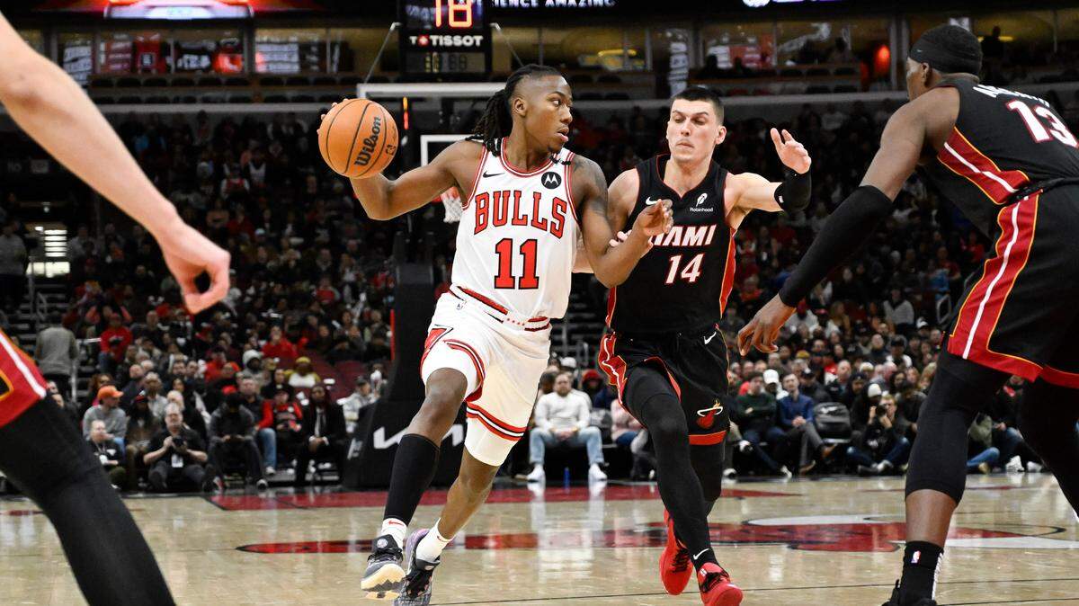 Chicago Bulls guard Ayo Dosunmu (11) moves the ball past Miami Heat guard Tyler Herro (14) during the first half at United Center.