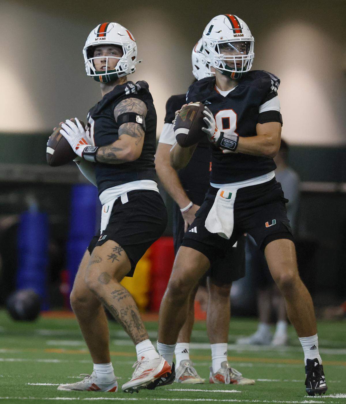 Miami Hurricanes quarterbacks Carson Beck (11) and Emory Williams (8), set up to pass during football practice at the Carol Soffer Indoor Practice Facility in Coral Gables, Florida, on Thursday, July 31, 2025.