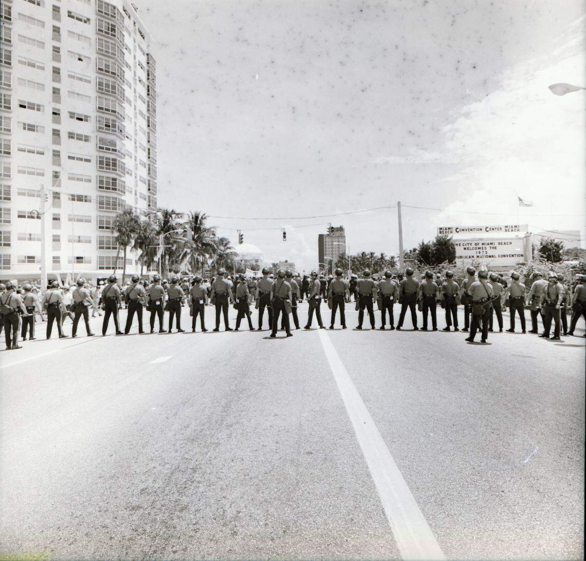 Vietnam War protesters face off against police on Washington Avenue with the Miami Beach Convention Center in the background.