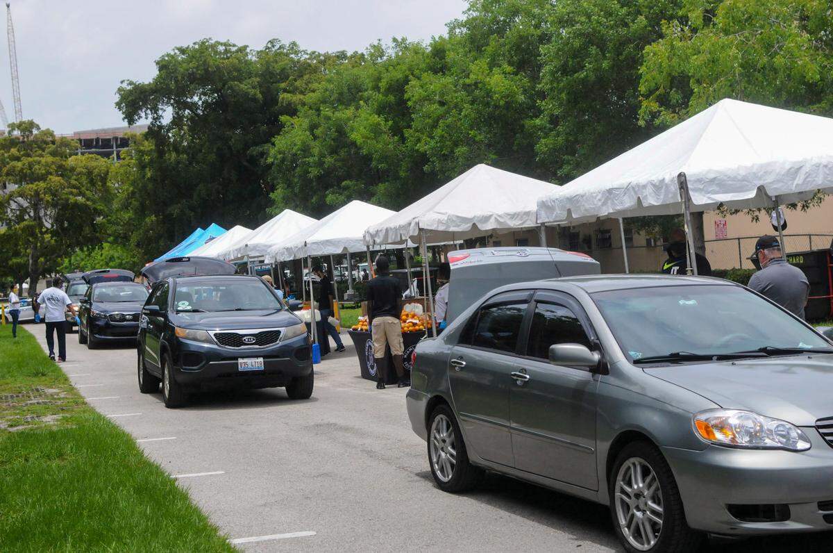 Cars drive past various stations at a parking lot next to Marlins Park during one of the Miami Marlins’ drive-thru food distributions on Wednesday, June 2, 2020.