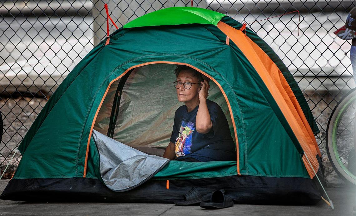 A homeless woman looks out from a tent set up under the I-95 underpass right across from a mobile vaccination site, part of the effort to give the homeless access to the COVID-19 vaccine, on May 21, 2021.