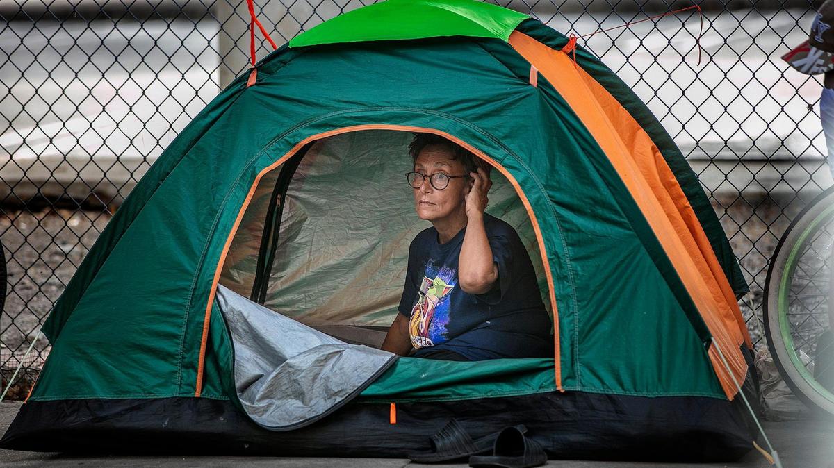 A homeless woman sits inside a tent beneath an Interstate 95 underpass in Miami-Dade County.