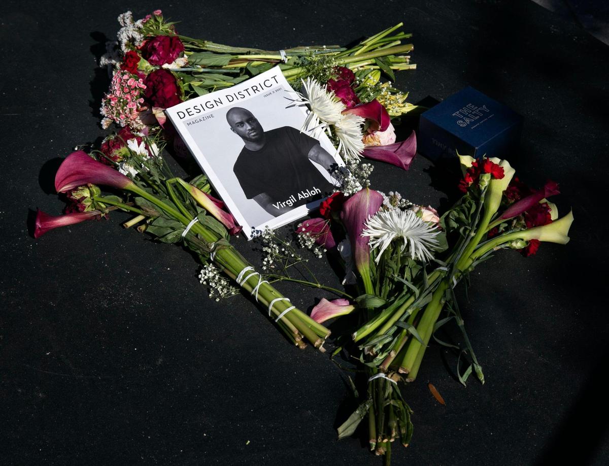 Flowers and a photo of Virgil Abloh, the artistic director of Louis Vuitton men’s wear as well as the founder of his own brand, Off-Whitetributes are placed in honor of Abloh at the foot of a giant statue of a model wearing his clothing design as part of a tribute Friday, December 3, 2021 in the Design District.