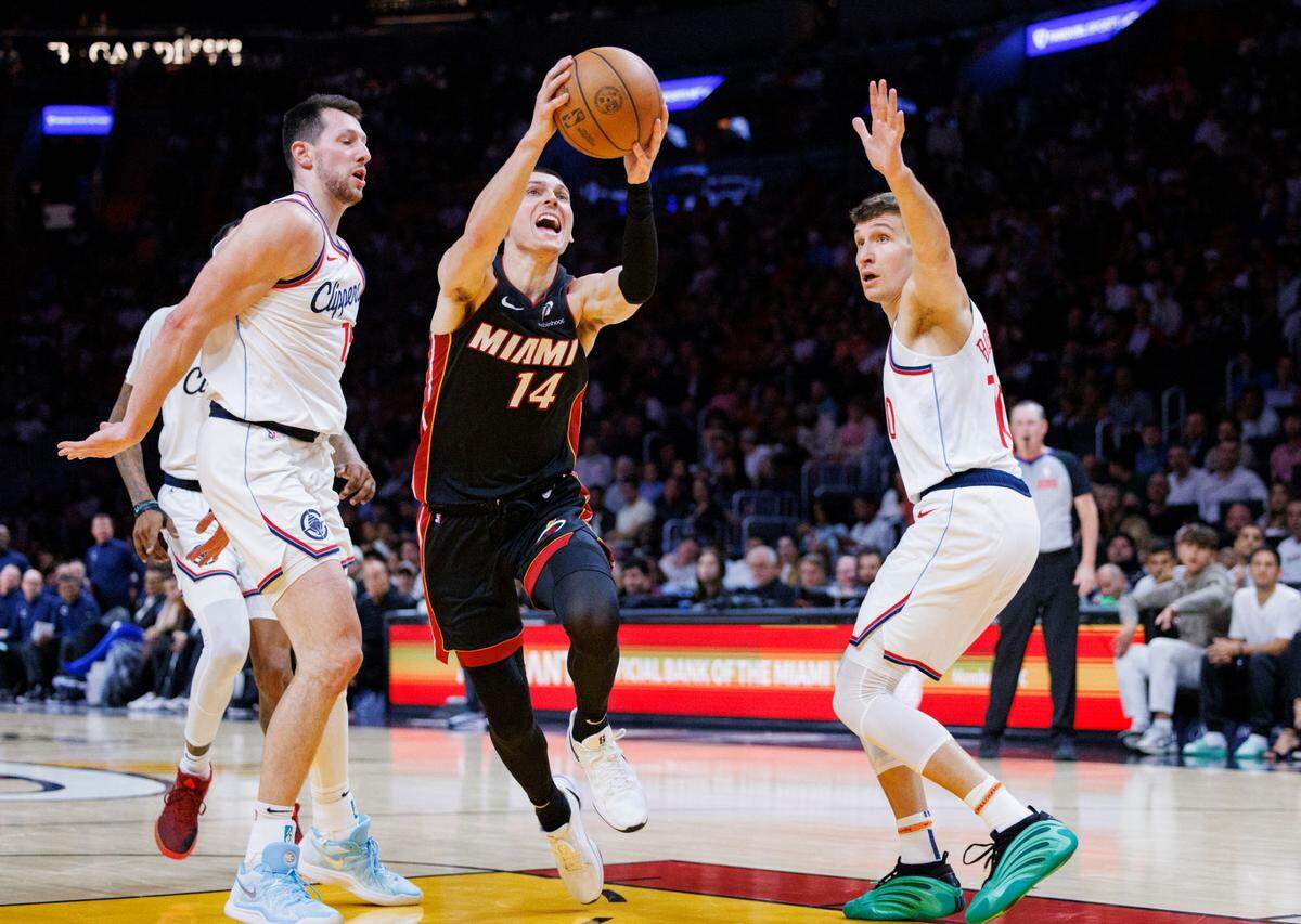Miami Heat guard Tyler Herro (14) dribble between LA Clippers forward Drew Eubanks (15) and guard Bogdan Bogdanovic (10) during the second half of a game on Wednesday, March 12, 2025, at the Kaseya Center in downtown Miami, Fla.
