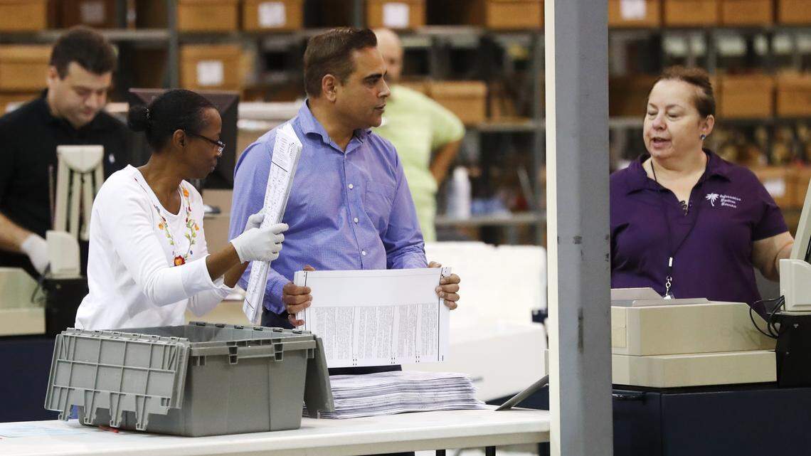 Employees at the Palm Beach County Supervisor of Elections office feed ballots through a machine Tuesday, Nov. 13, during the ongoing recount as they race to make a Thursday deadline.