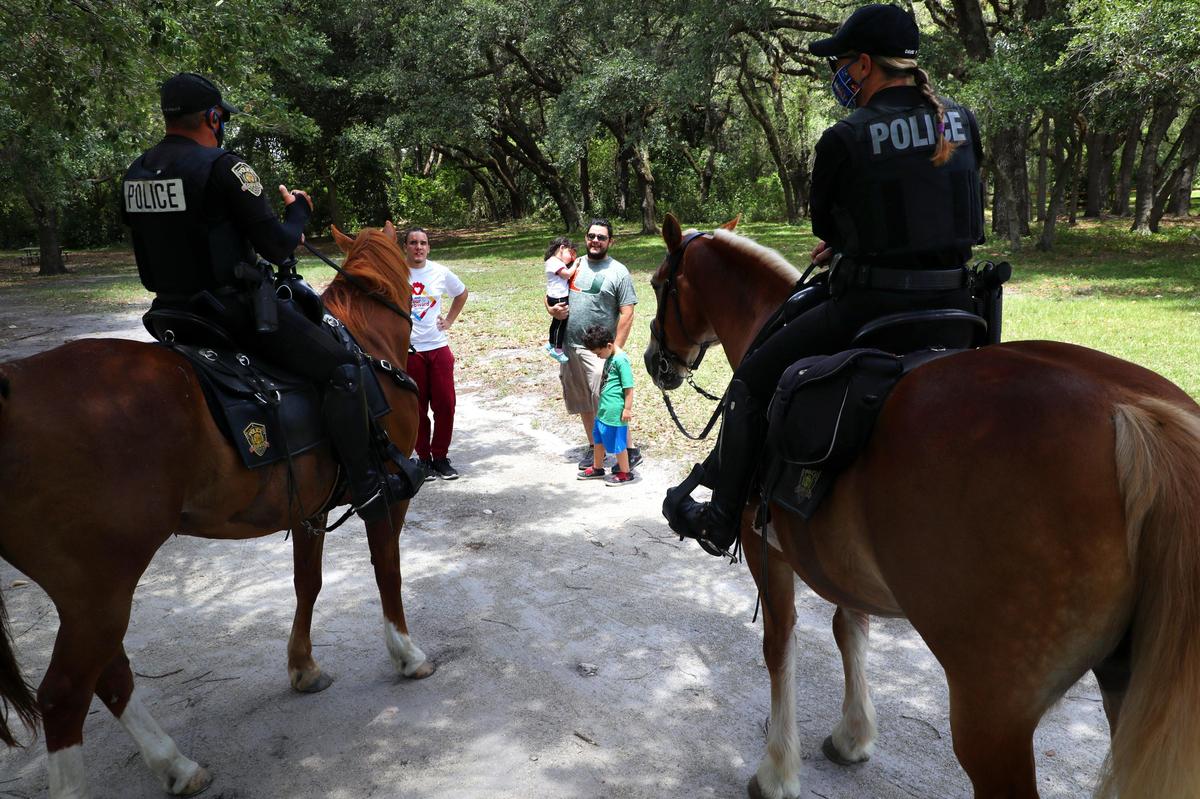 Davie mounted police officers greet a family while enforcing social distancing at Tree Top Park in Davie. Palm Beach Broward and Miami Dade counties reopened county parks with some limitations aiming to keep people apart on April 29,2020. ...SOUTH FLORIDA OUT; NO MAGS; NO SALES; NO INTERNET; NO TV...