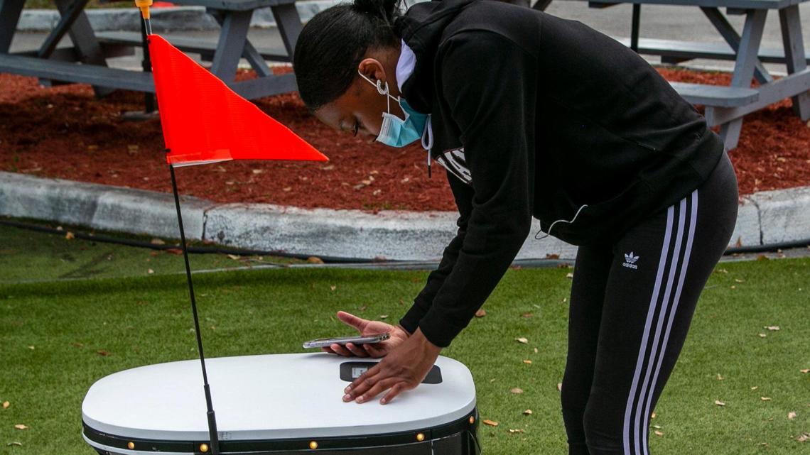 Miami, Florida, March 30, 2021 - Dominique Peters, a REEF employee, demonstrates how to plug in the code to open the lid to get the order. REEF, the largest operator of parking lots and neighborhood hubs in North America, officially launched its first robot delivery service in Miami’s downtown.