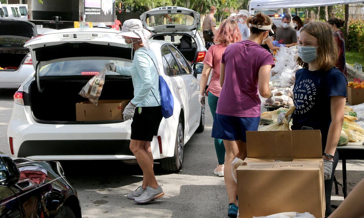 Volunteers load up food and vegetables to hundreds of cars lined up for hours early Saturday at a food giveaway sponsored by Farm Share of Florida at the Gibson-Bethel Community Center in the city of South Miami to alleviate and help many families that are in need due to the pandemic coronavirus Covid-19 outbreak, on Saturday, April 18, 2020.